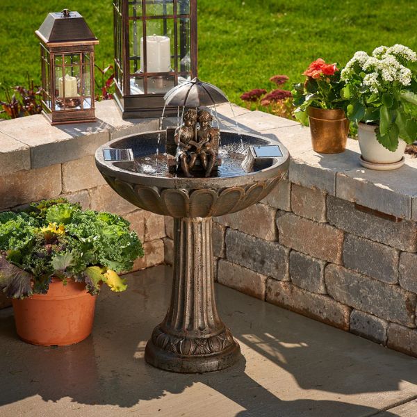 Decorative outdoor birdbath with stone wall and potted plants