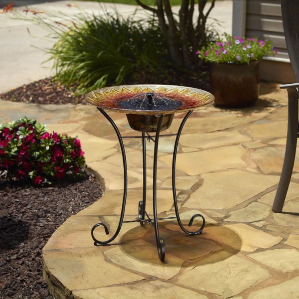 Decorative outdoor bird bath with solar light on a stone patio