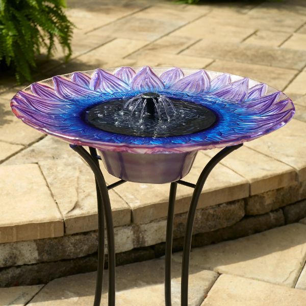 Decorative solar bird bath with purple and blue design on a patio