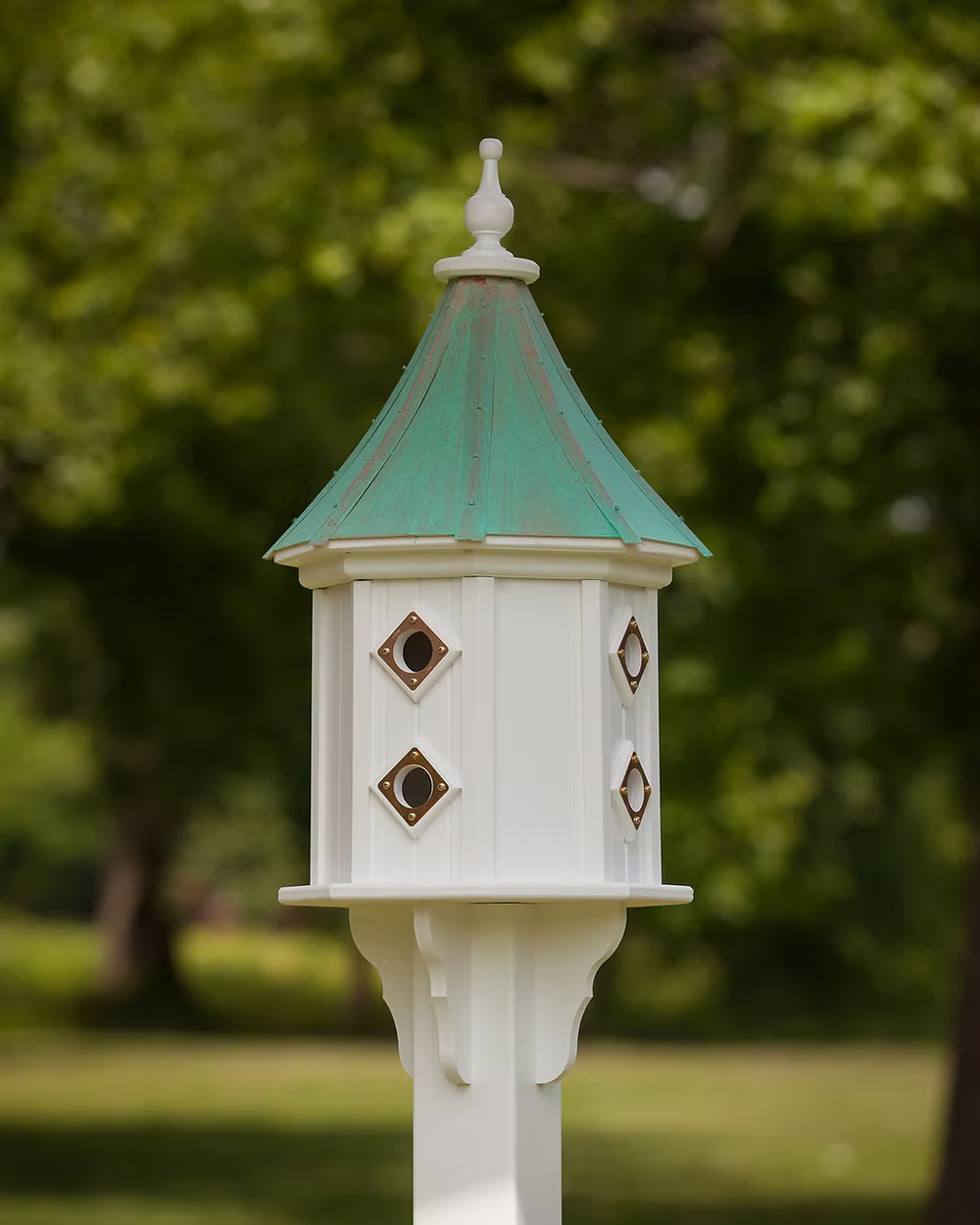 White birdhouse with a green roof against a blurred green background