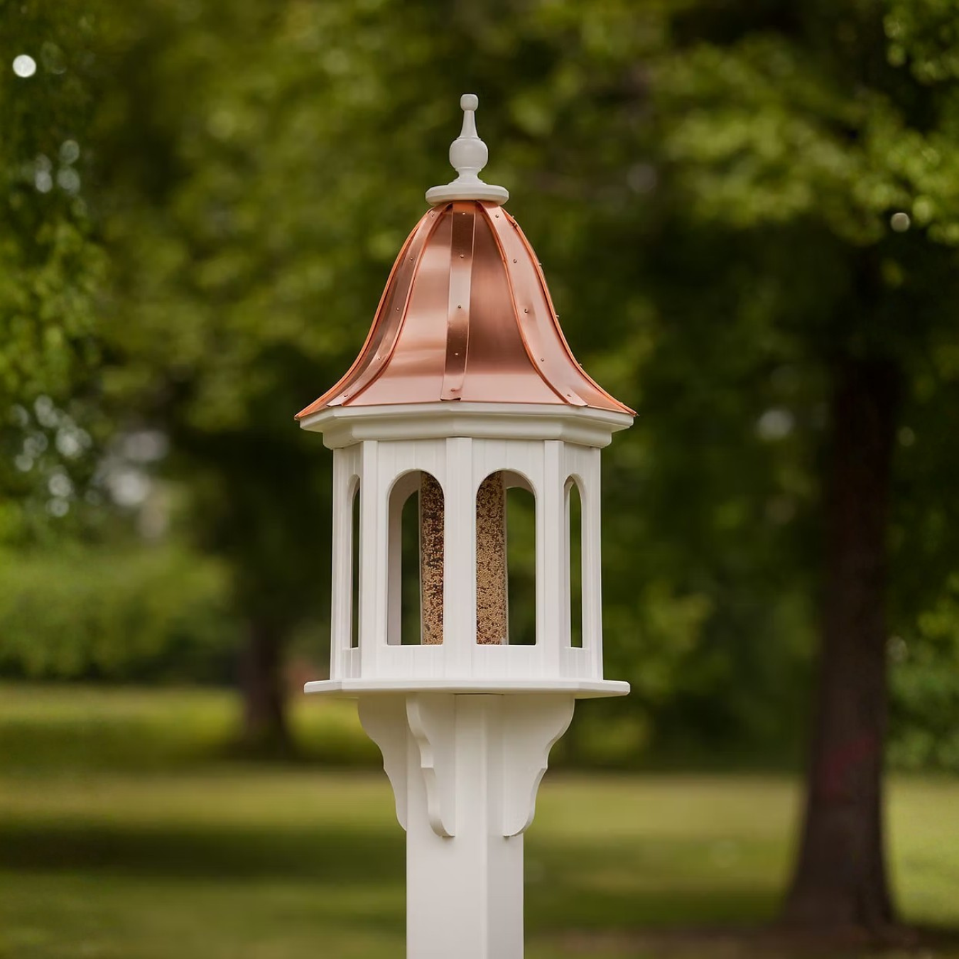 Decorative bird feeder with a copper roof in a garden setting