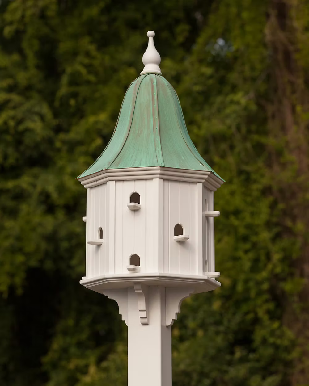 Decorative birdhouse with a green roof against a blurred natural background