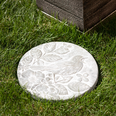 Songbird Stepping Stone – Round cement stepping stone with a carved gray, stone-like finish. Features embossed flowers, leaves, and a delicate bird design. Durable and weather-resistant, perfect for gardens, pathways, or decorative displays. Measures 11"L x 11"W x 1"H. Adds a charming, nature-inspired touch to any outdoor space.
