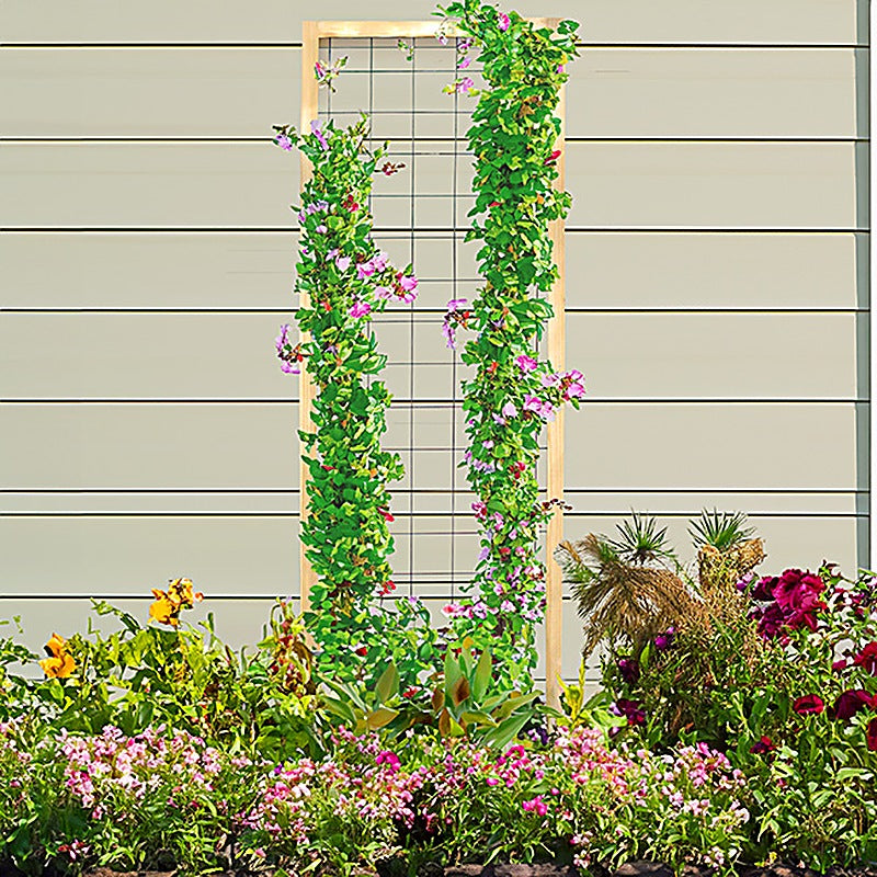 Cedar and steel wire grid garden trellis covered in flowering vines in front of a house wall