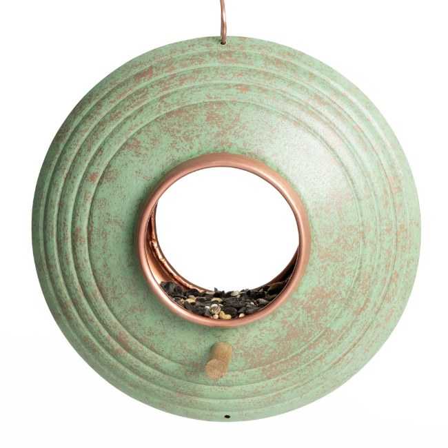 Front view of the Fly-Thru™ bird feeder showcasing its circular design with a large copper-ringed opening filled with bird seed.