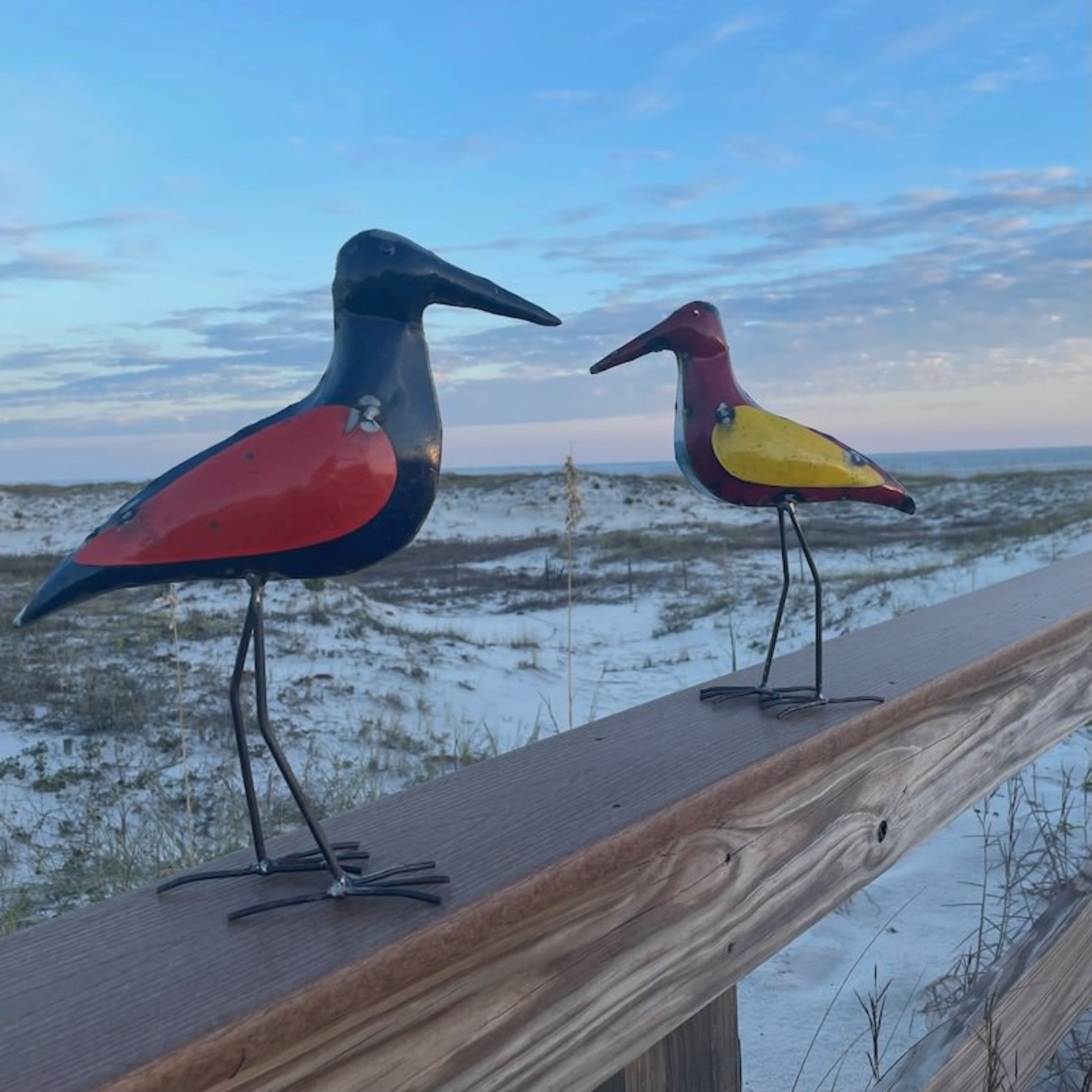 Sandpiper metal art resting on wooden post with beach in background