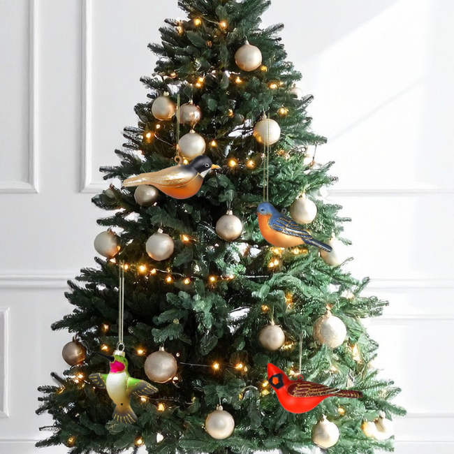 Decorated Christmas tree with bird-shaped ornaments and string lights against a white wall.