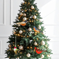 Decorated Christmas tree with bird-shaped ornaments and string lights against a white wall.