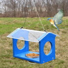 Blue bird feeder with a bird flying towards it in an outdoor setting