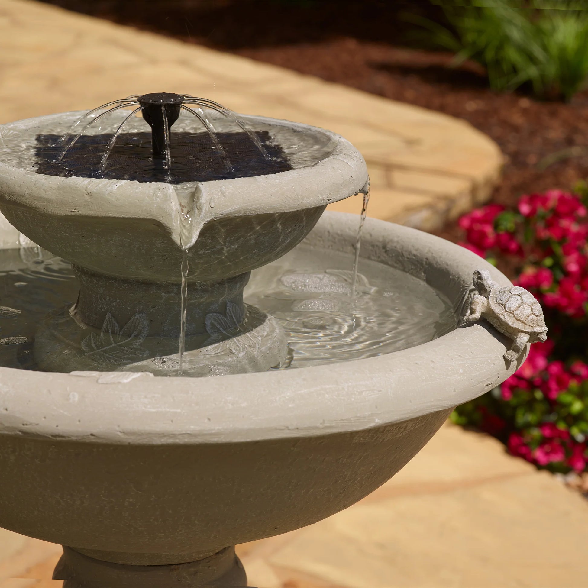 Detailed view of the two-tier garden fountain featuring a small turtle figurine on the edge and a solar panel powering the water spout.
