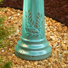 Turquoise decorative column with cut-out patterns on a pebble ground