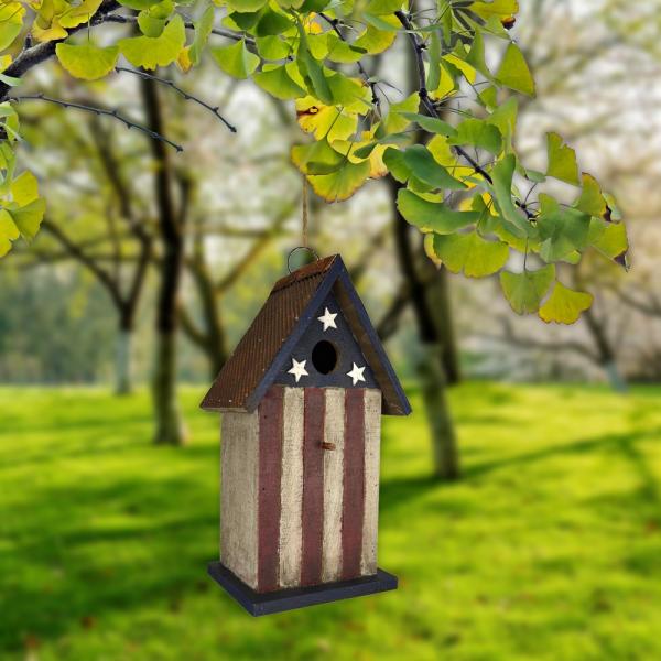 Decorative birdhouse with American flag design hanging from a tree branch.