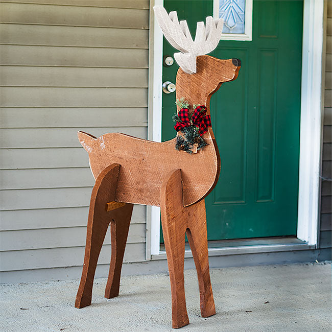 Wooden deer decoration with antlers and a bow tie in front of a green door.