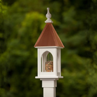 Decorative bird feeder with a copper roof against a blurred green background