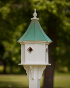 White birdhouse with a green roof against a blurred green background