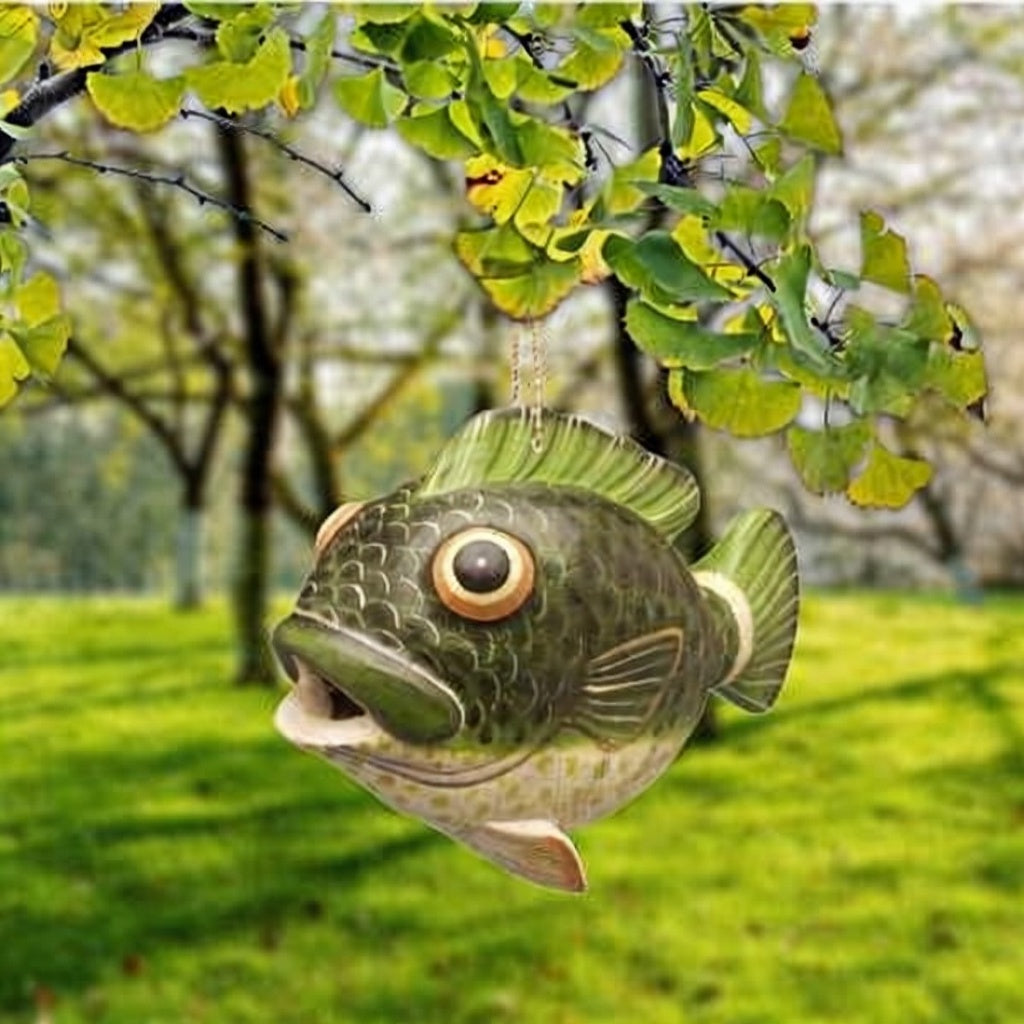 Decorative fish hanging from a tree with a blurred green and brown background