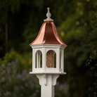 Decorative bird feeder with copper roof against a blurred natural background