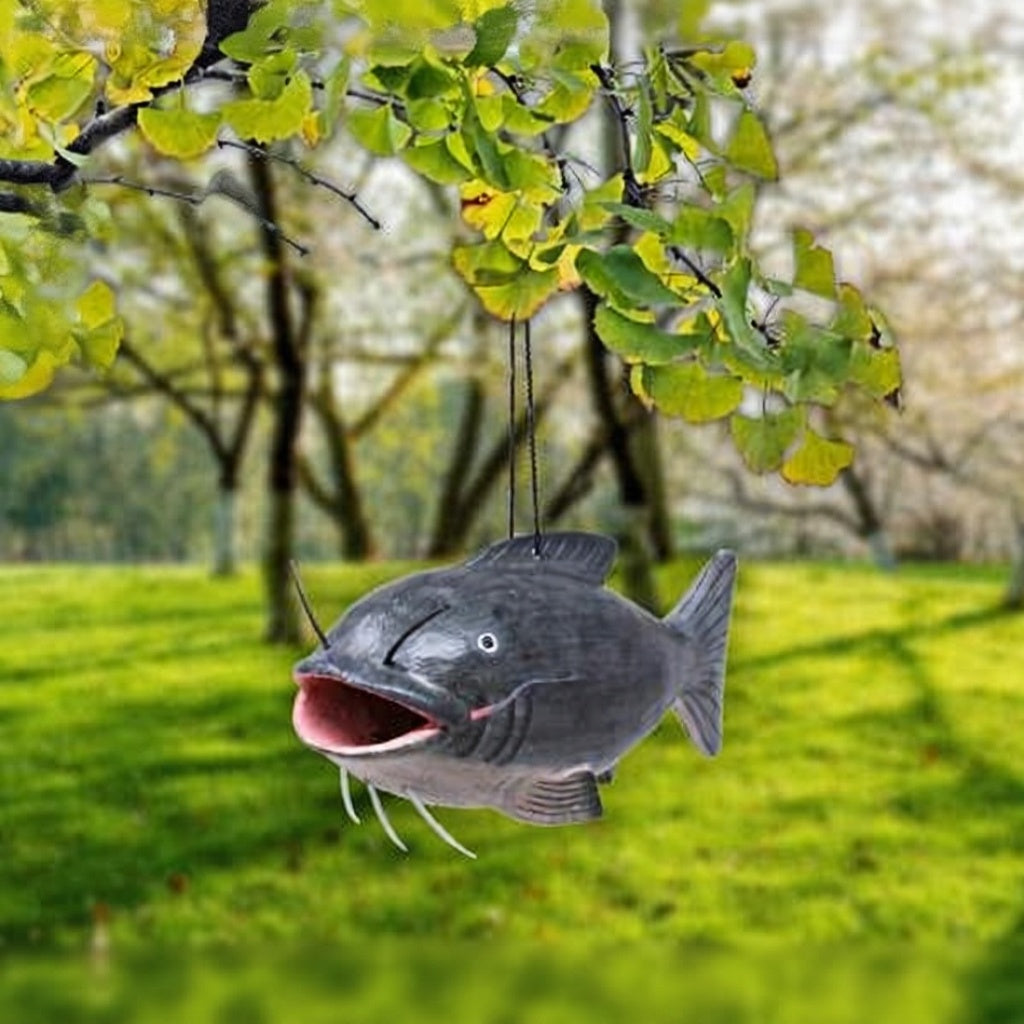 Fish-shaped bird feeder hanging from a tree in a park setting
