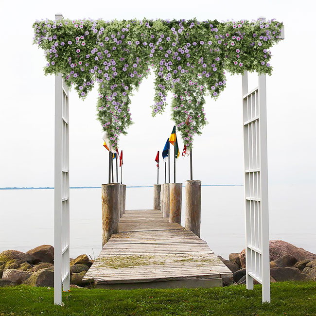 The Classic Garden Arbor, framed with cascading petunias, provides an elegant entrance to a lakeside pier, showcasing its versatile design.