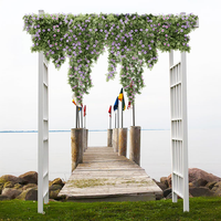 The Classic Garden Arbor, framed with cascading petunias, provides an elegant entrance to a lakeside pier, showcasing its versatile design.
