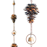 Close-up of a single copper pine cone with flamed copper finish and a bell in the middle, hanging on a chain.
