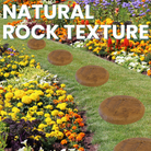 Two handcrafted dragonfly garden stepping stones placed along a colorful garden path with flowers, featuring an autumn wheat finish.