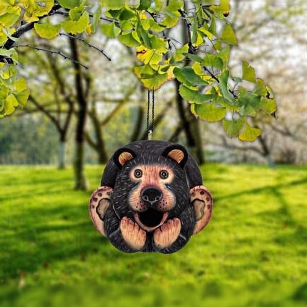 Bear-shaped ornament hanging from a tree in a park setting