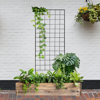  The Gridlock Garden Trellis standing against a wall with cascading vines, paired with a wooden planter box full of vibrant indoor plants.

