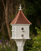 White birdhouse with a copper roof against a natural background