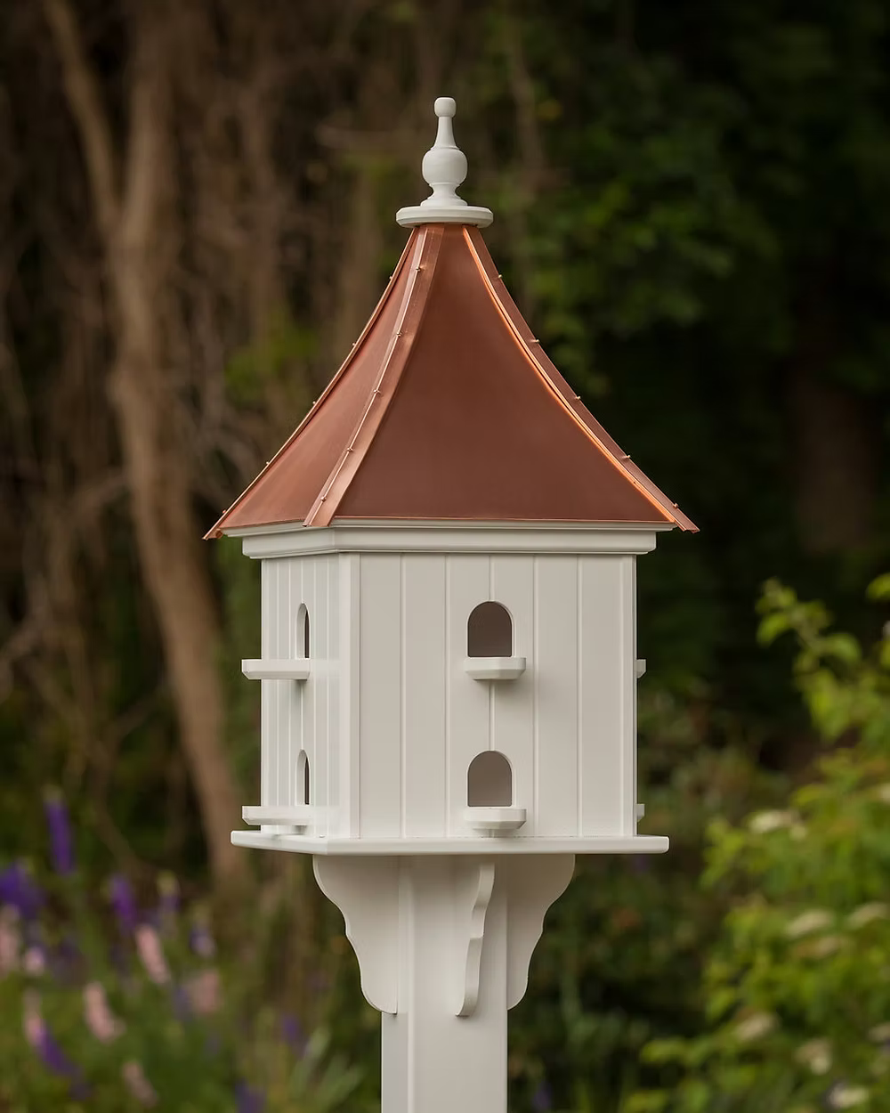 White birdhouse with a copper roof against a natural background