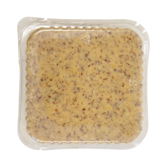 Vacuum-sealed plastic pouch of grainy mustard with speckled brown seeds visible through clear packaging. The mustard's texture appears thick and coarse.