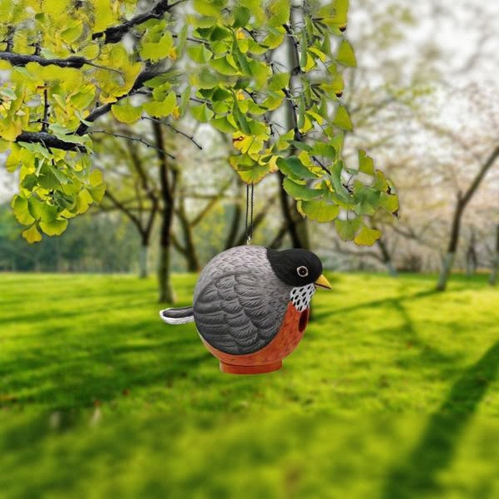 Decorative bird ornament hanging from a tree branch in a park setting