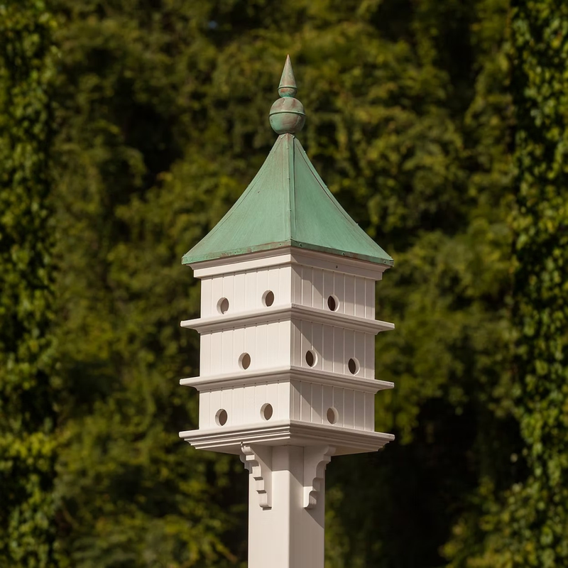 Classic Purple Martin birdhouse with a patina copper roof against a blurred green background