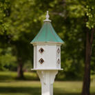 White octagon birdhouse with multiple copper portals for entry and a patina copper roof in a garden setting