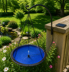 Blue bird bath with solar panel on a wooden deck in a garden setting