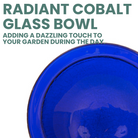 Solar-powered cobalt glass birdbath with a fountain feature, surrounded by lush plants and flowers in the garden, offering a delightful birdbathing experience.