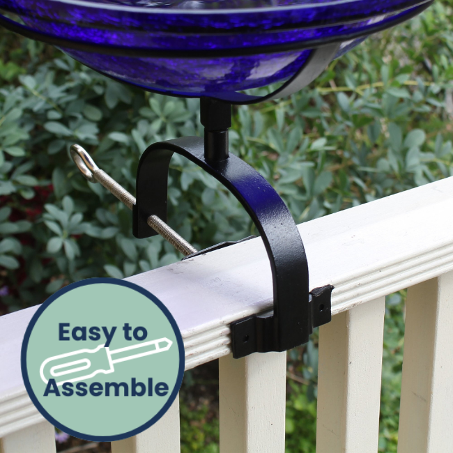 Solar-powered crackle glass birdbath mounted on a porch railing with a black wrought iron stand and a bird perched nearby.