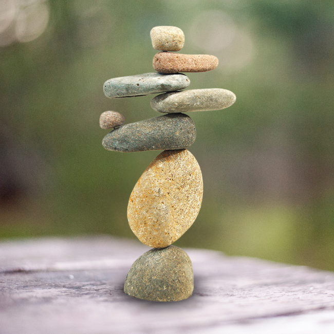 Zen Balance Stone Stack displayed in a garden with different sizes and textures of river stones stacked thoughtfully.