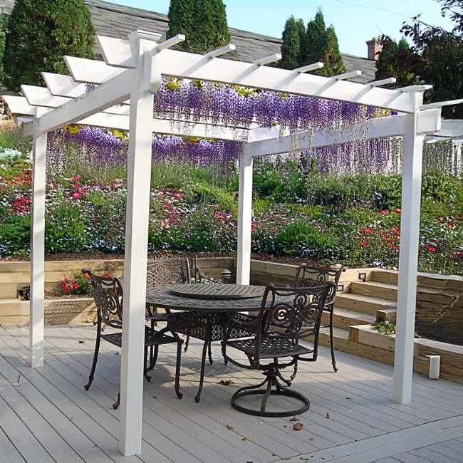 The BreezeWay White Pergola showcasing purple wisteria climbing over the structure, adding a dynamic and enchanting element to your garden. Its durable white vinyl frame offers both beauty and functionality.