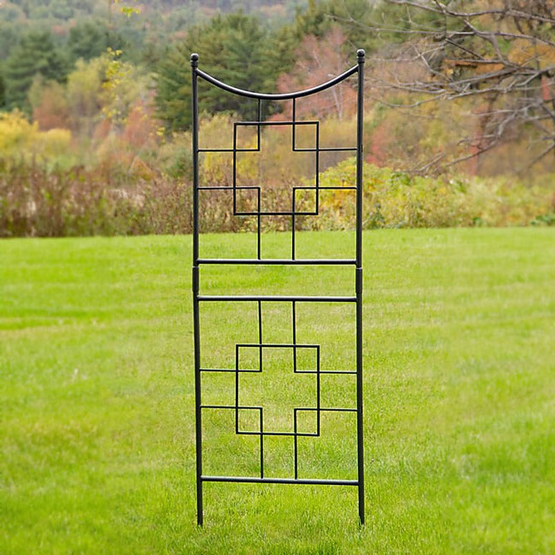 Graphite geometric wrought iron garden trellis standing on a green lawn