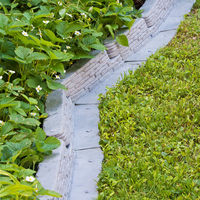 Stacked Stone Garden Border installed in a corner, showing the interlocking design and creating a natural stone appearance along the edge.